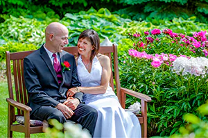 A bride and groom take a moment to pause on a bench