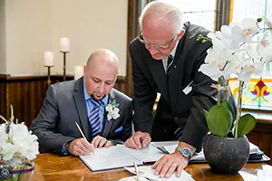 A groom signs his name on legal documents