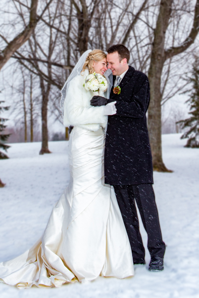 A bride and groom embrace eachother in the cold snow